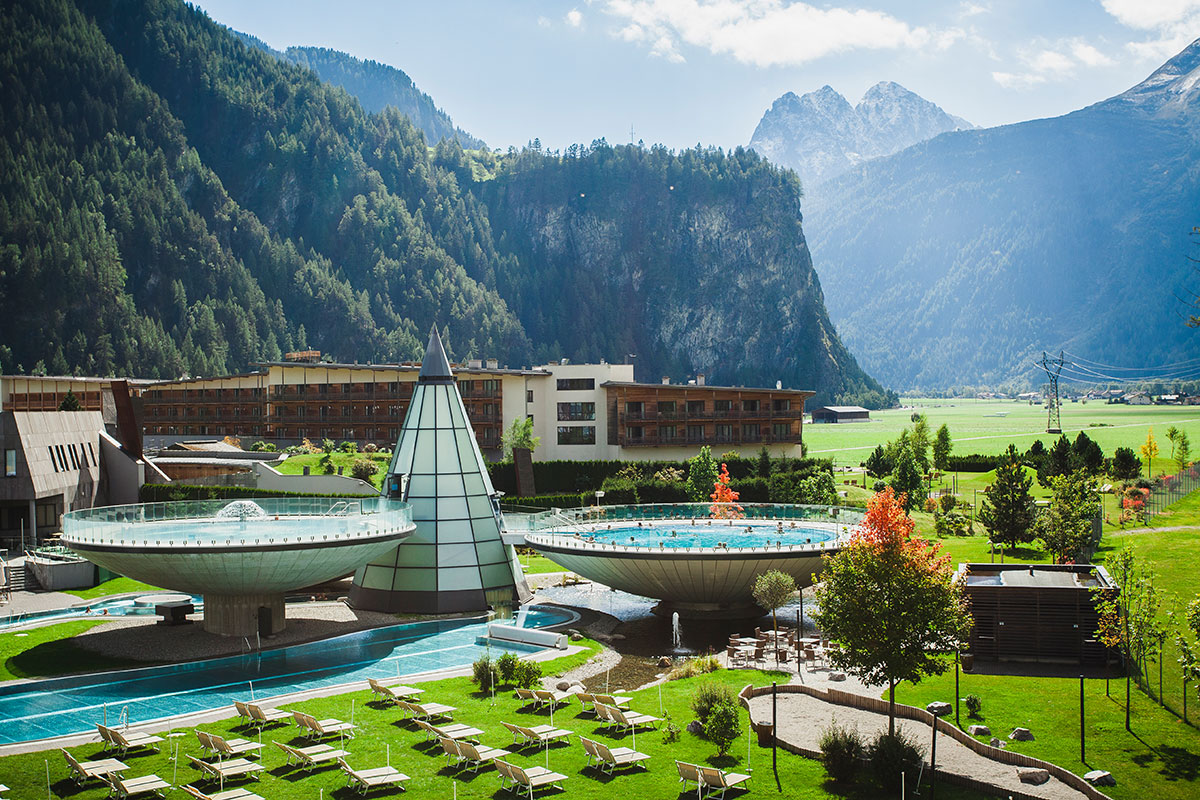 AQUA DOME: termální část s hotelovou budovou v pozadí a alpskou krajinou